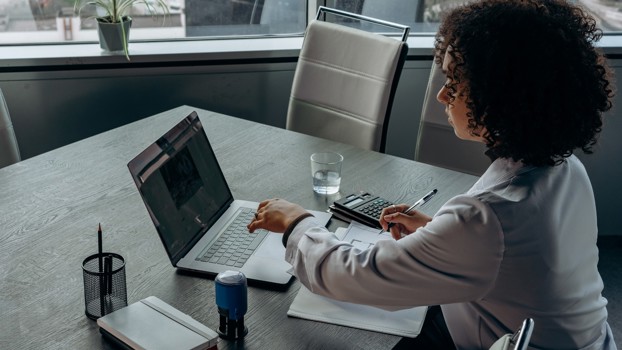 Woman Sitting With Laptop At Her Desk